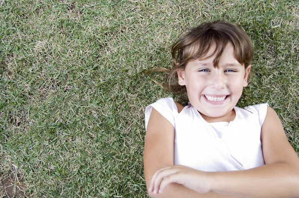 Sorrindo jovem bonito menina deitada na grama — Fotografia de Stock