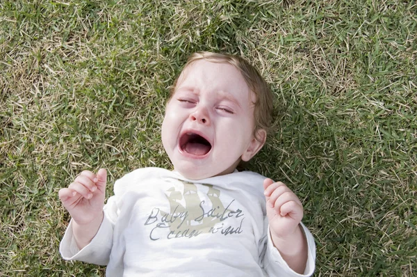 Красивый ребенок плачет в саду — стоковое фото