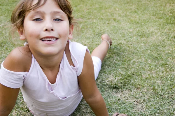 Schönes junges Mädchen im Gras liegend — Stockfoto