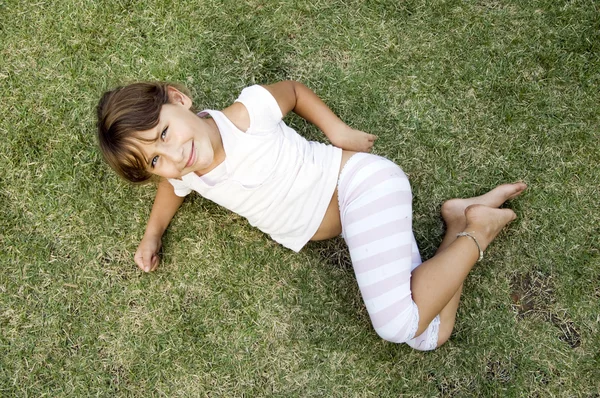 Χαμογελαστός νεαρός χαριτωμένο κορίτσι ξαπλωμένος στο γρασίδι — Φωτογραφία Αρχείου