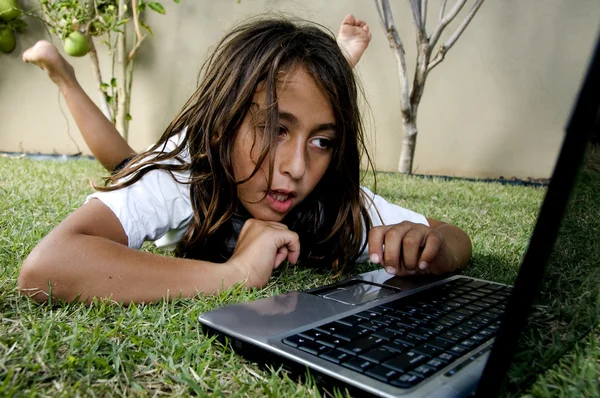 Мальчик работает на ноутбуке, лежит на траве — стоковое фото