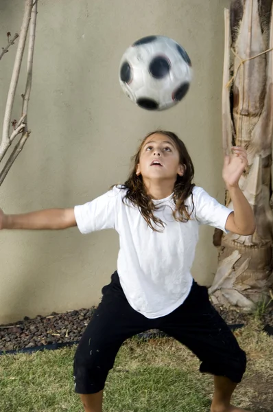 Menino balanceamento bola de futebol na cabeça — Fotografia de Stock