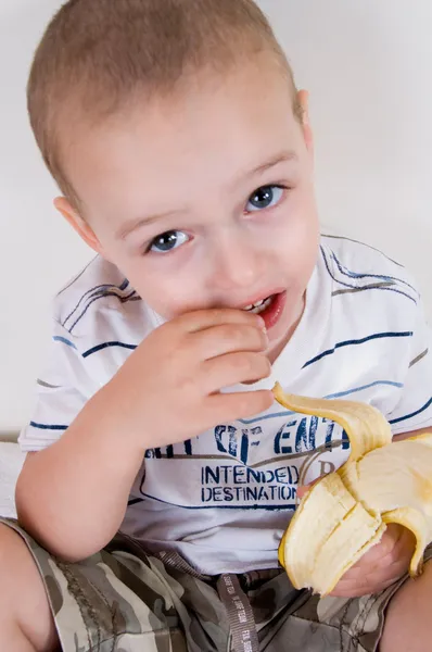 Bonito menino segurando banana descascada — Fotografia de Stock