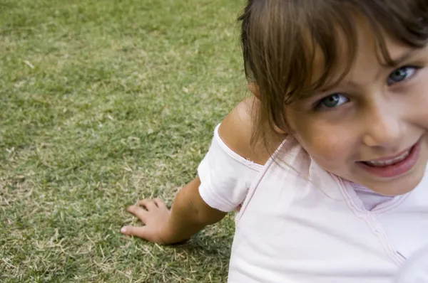 Usměvavá holčička seděli na trávě — Stock fotografie