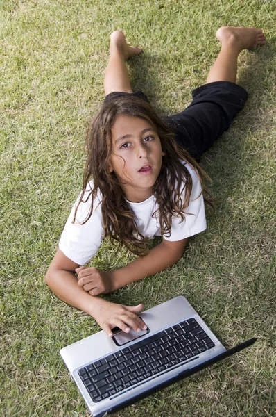 Маленький мальчик лежит на траве с ноутбуком — стоковое фото
