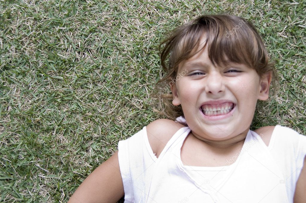Young girl on grass with clenched teeth
