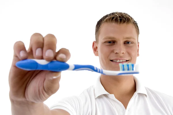Чоловік показує зубну щітку, посміхаючись — стокове фото
