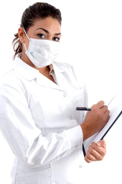 Ženský lékař s maskou psaní na podložce — Stock fotografie