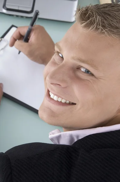 Postura traseira de homem sorridente escrevendo no pad — Fotografia de Stock