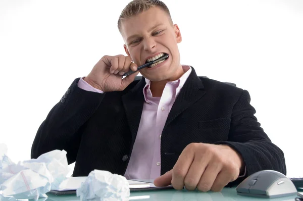Frustrated man biting pen with teeth — Stock Photo, Image