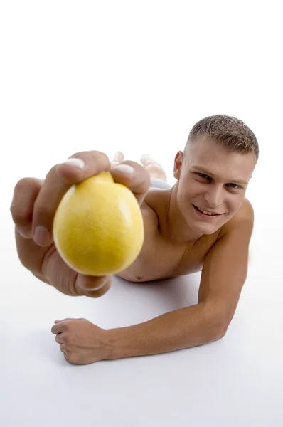 Sorrindo homem muscular mostrando laranja — Fotografia de Stock
