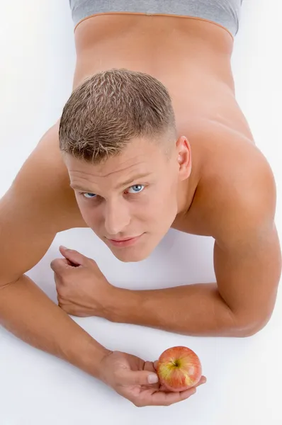 Молодой человек без рубашки держит яблоко — стоковое фото