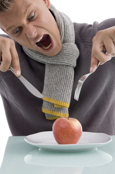 Homem irritado com maçã com garfo e faca — Fotografia de Stock