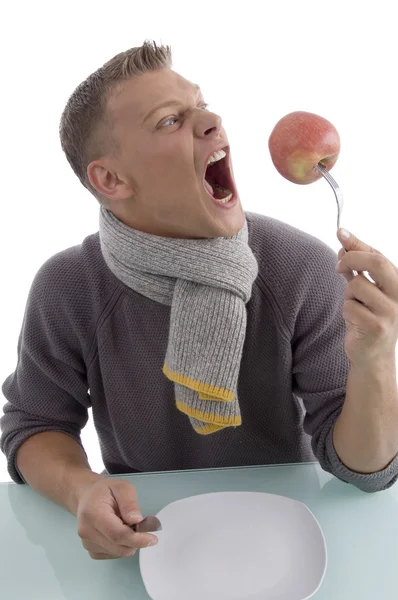 Злой человек держит яблоко вилкой — стоковое фото