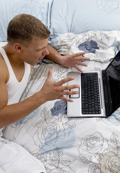 Αρσενικό που εργάζονται στο lap-top στο κρεβάτι — Φωτογραφία Αρχείου