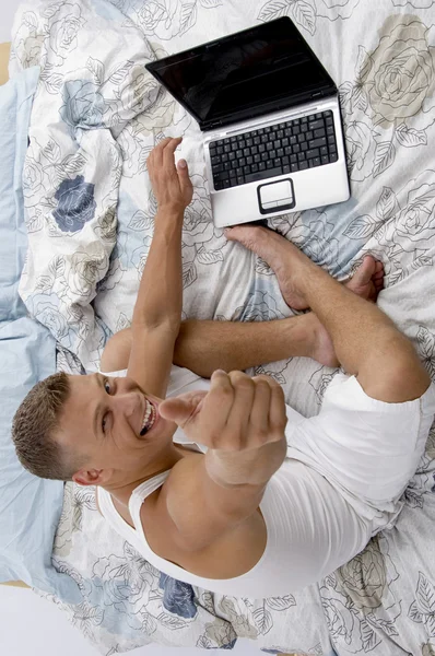 Vista superior del hombre con ordenador portátil en la cama —  Fotos de Stock