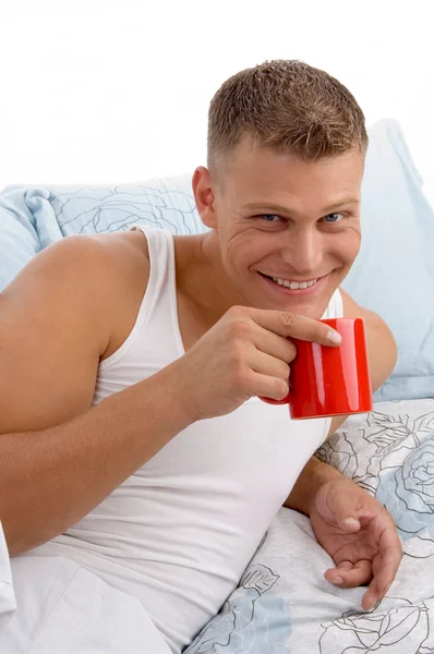 微笑着躺在床上的男性喝咖啡 — 图库照片