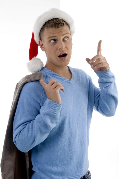 Junger Mann mit Weihnachtsmütze zeigt nach oben — Stockfoto