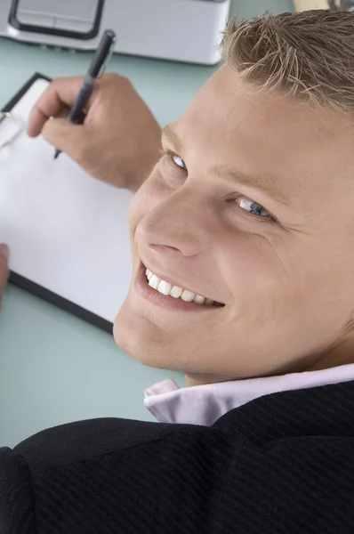Posada trasera del hombre sonriente escribiendo en la almohadilla Imagen De Stock