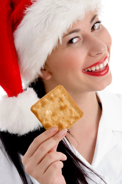 Mulher com chapéu de Natal segurando biscoito — Fotografia de Stock