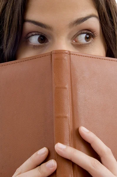 Close up of student peeping from book — Stock Photo, Image