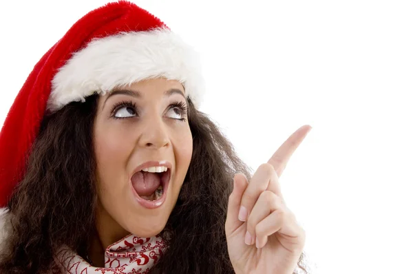 Молодая женщина в рождественской шляпе указывает — стоковое фото