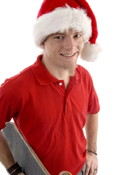Людина в різдвяній шапці зі скейтбордом — стокове фото