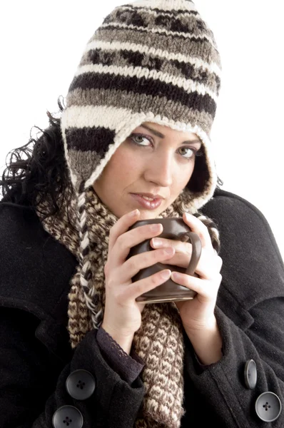 Χαμογελαστή γυναίκα, φορώντας ακουστικάコーヒーのマグカップを保持している冬の帽子を持つ女性 — ストック写真