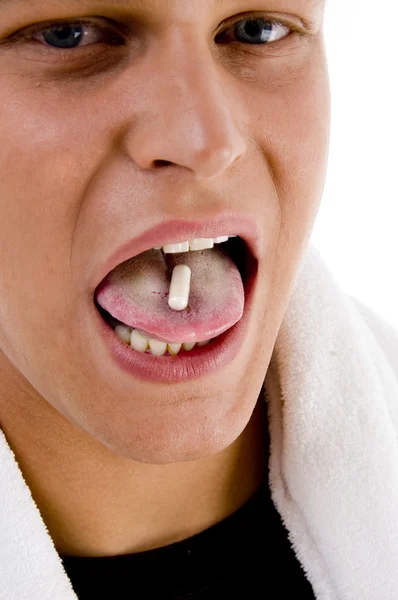 Mladý muž dát pilulku na svůj jazyk — Stock fotografie