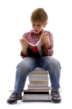 Boy sitting on pile of books and reading clipart