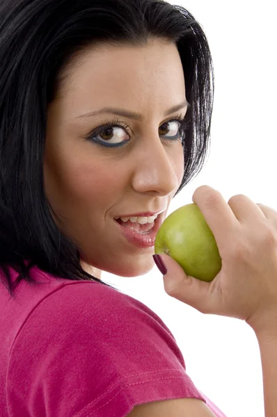 Posada lateral de hembra sonriente comiendo manzana — Foto de Stock