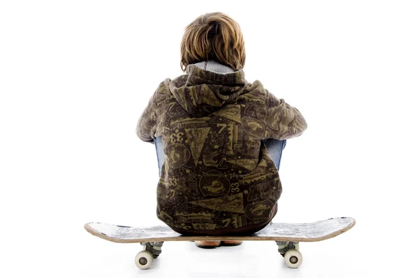 Поза сзади мальчика, сидящего на скейтборде — стоковое фото