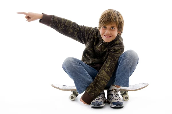 Front view of boy sitting on skateboard — Stock fotografie