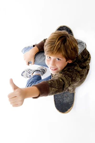 Хлопчик сидить на скейтборді, великі пальці вгору — стокове фото