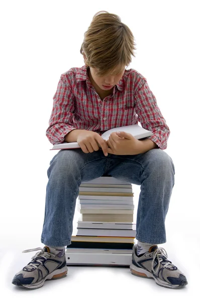 Vista frontal do menino sentado em livros — Fotografia de Stock