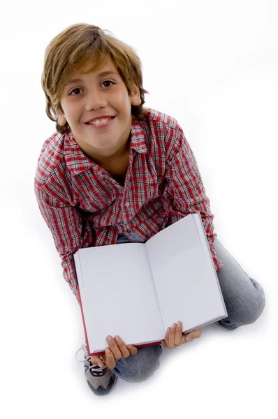 開かれた本に座っている少年の正面図 — ストック写真