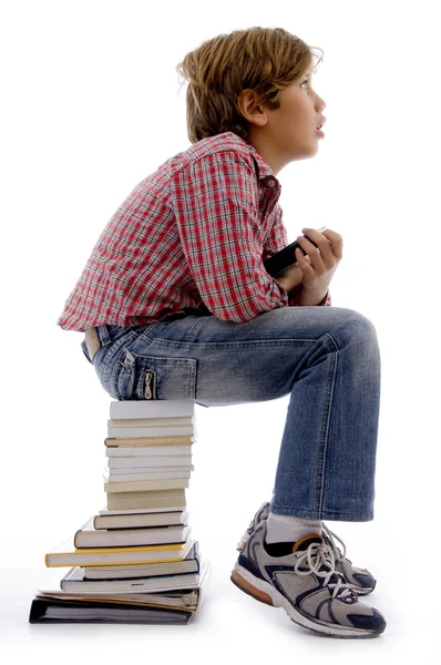 Kitap yığını üzerinde oturan genç çocuk — Stok fotoğraf
