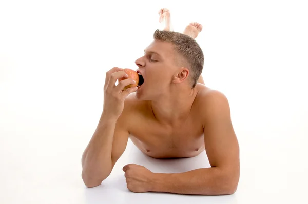Mladý muž na podlaze těší jablko — Stock fotografie