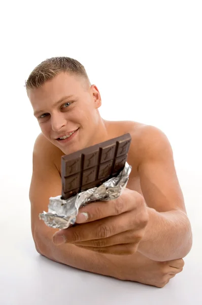 Lächelnder muskulöser Mann zeigt Schokolade — Stockfoto