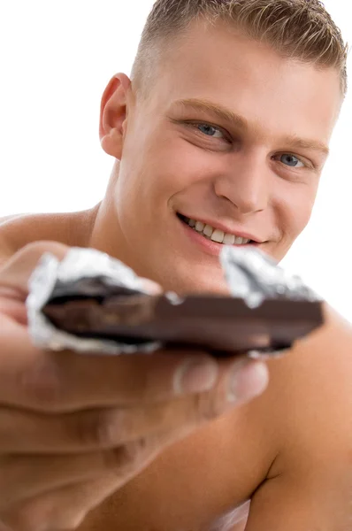 Muscular man offering chocolate — Stock Photo, Image