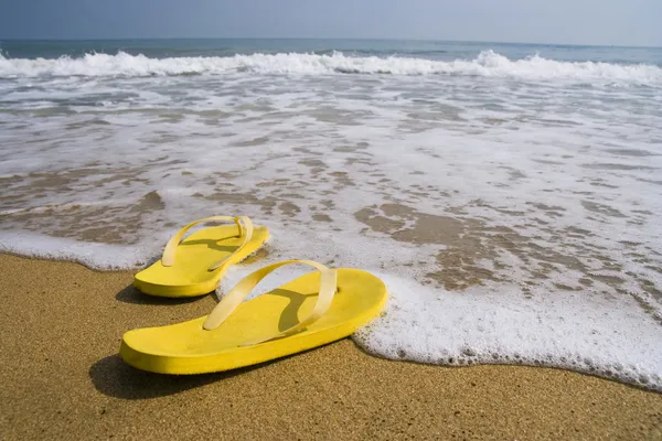 Plážové pantofle na písečné pláži, v létě — Stock fotografie