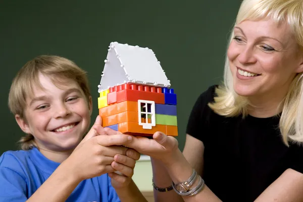 Kvinnan och pojken håll en leksak hus — Stockfoto