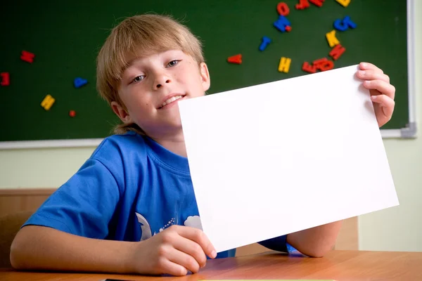 Pojken håller upp vita pappersark — Stockfoto