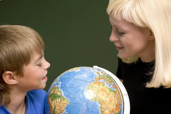 Pojke och ung kvinna ser på globe — Stockfoto