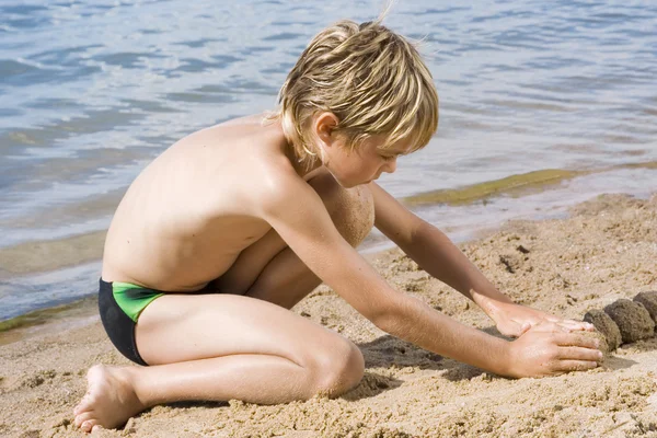 Roztomilý malý chlapec v písku — Stock fotografie