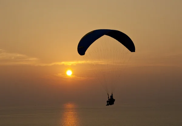 Parashutist nad mořem při západu slunce — Stock fotografie