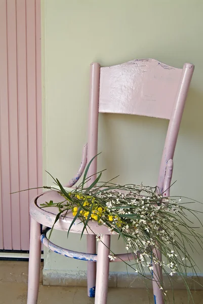 Cadeira rosa velha e flores — Fotografia de Stock
