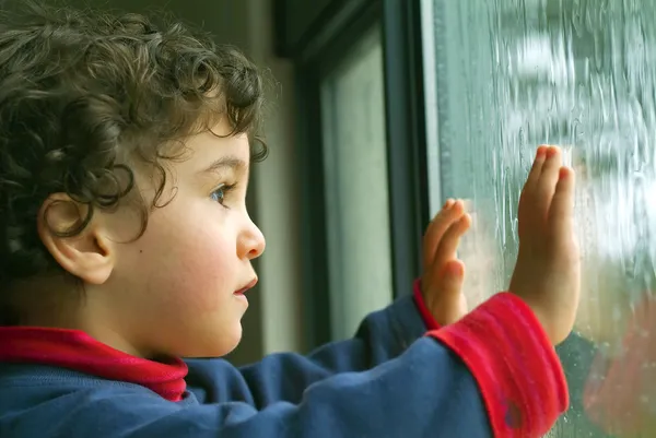 Маленький хлопчик дивиться дощ Стокова Картинка