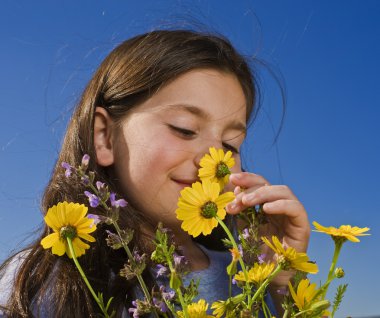 Young girl smelling flowers clipart