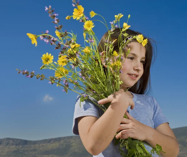 Chica joven sosteniendo flores — Foto de Stock